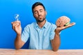 Handsome hispanic man holding lightbulb and brain for inspiration and idea looking at the camera blowing a kiss being lovely and Royalty Free Stock Photo