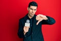 Handsome hispanic man holding reporter microphone with angry face, negative sign showing dislike with thumbs down, rejection Royalty Free Stock Photo