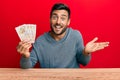 Handsome hispanic man holding united kingdom pounds celebrating achievement with happy smile and winner expression with raised