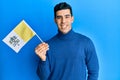 Handsome hispanic man holding vatican city flag looking positive and happy standing and smiling with a confident smile showing Royalty Free Stock Photo