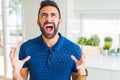 Handsome hispanic man at home crazy and mad shouting and yelling with aggressive expression and arms raised Royalty Free Stock Photo