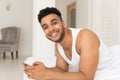 Handsome Hispanic Man Lying In Bed Using Cell Smart Phone, Young Guy Happy Smile Royalty Free Stock Photo