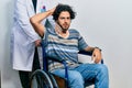 Handsome hispanic man sitting on wheelchair wearing neck collar confuse and wonder about question Royalty Free Stock Photo
