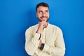 Handsome hispanic man standing over blue background with hand on chin thinking about question, pensive expression Royalty Free Stock Photo