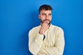 Handsome hispanic man standing over blue background with hand on chin thinking about question, pensive expression Royalty Free Stock Photo