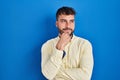 Handsome hispanic man standing over blue background with hand on chin thinking about question, pensive expression Royalty Free Stock Photo