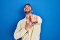 Handsome hispanic man standing over blue background laughing at you, pointing finger to the camera with hand over body, shame Royalty Free Stock Photo