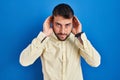 Handsome hispanic man standing over blue background trying to hear both hands on ear gesture, curious for gossip Royalty Free Stock Photo