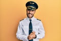 Handsome hispanic man wearing airplane pilot uniform with hands together and crossed fingers smiling relaxed and cheerful