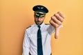 Handsome hispanic man wearing airplane pilot uniform looking unhappy and angry showing rejection and negative with thumbs down Royalty Free Stock Photo