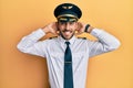 Handsome hispanic man wearing airplane pilot uniform relaxing and stretching, arms and hands behind head and neck smiling happy Royalty Free Stock Photo