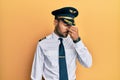 Handsome hispanic man wearing airplane pilot uniform tired rubbing nose and eyes feeling fatigue and headache Royalty Free Stock Photo