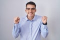 Handsome hispanic man wearing business clothes and glasses excited for success with arms raised and eyes closed celebrating Royalty Free Stock Photo