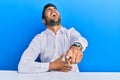 Handsome hispanic man wearing business clothes sitting on the table laughing at you, pointing finger to the camera with hand over Royalty Free Stock Photo