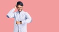 Handsome hispanic man wearing business shirt and glasses looking at the watch time worried, afraid of getting late Royalty Free Stock Photo