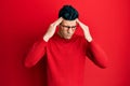 Handsome hispanic man wearing casual clothes and glasses with hand on head, headache because stress Royalty Free Stock Photo