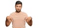 Handsome hispanic man wearing casual clothes pointing down looking sad and upset, indicating direction with fingers, unhappy and Royalty Free Stock Photo