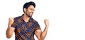 Handsome hispanic man wearing casual clothes very happy and excited doing winner gesture with arms raised, smiling and screaming Royalty Free Stock Photo