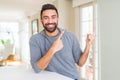 Handsome hispanic man wearing casual sweatshirt at home smiling and looking at the camera pointing with two hands and fingers to Royalty Free Stock Photo
