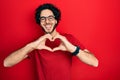 Handsome hispanic man wearing casual t shirt and glasses smiling in love doing heart symbol shape with hands Royalty Free Stock Photo