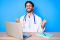 Handsome hispanic man wearing doctor uniform working at the clinic celebrating surprised and amazed for success with arms raised Royalty Free Stock Photo