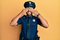 Handsome hispanic man wearing police uniform covering eyes with hands smiling cheerful and funny Royalty Free Stock Photo