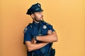 Handsome hispanic man wearing police uniform looking to the side with arms crossed convinced and confident Royalty Free Stock Photo