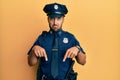 Handsome hispanic man wearing police uniform pointing down looking sad and upset, indicating direction with fingers, unhappy and Royalty Free Stock Photo