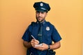 Handsome hispanic man wearing police uniform writing traffic fine skeptic and nervous, frowning upset because of problem