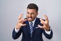 Handsome hispanic man wearing suit and tie shouting frustrated with rage, hands trying to strangle, yelling mad Royalty Free Stock Photo