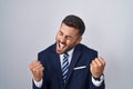 Handsome hispanic man wearing suit and tie very happy and excited doing winner gesture with arms raised, smiling and screaming for Royalty Free Stock Photo