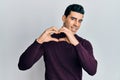 Handsome hispanic man wearing turtleneck sweater smiling in love doing heart symbol shape with hands