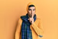 Handsome hispanic man wearing wool hat and winter scarf asking to be quiet with finger on lips Royalty Free Stock Photo