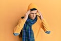 Handsome hispanic man wearing wool hat and winter scarf with hand on head for pain in head because stress Royalty Free Stock Photo