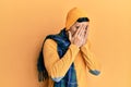 Handsome hispanic man wearing wool hat and winter scarf with sad expression covering face with hands while crying Royalty Free Stock Photo