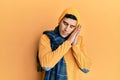 Handsome hispanic man wearing wool hat and winter scarf sleeping tired dreaming and posing with hands together while smiling with Royalty Free Stock Photo