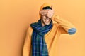 Handsome hispanic man wearing wool hat and winter scarf smiling and laughing with hand on face covering eyes for surprise Royalty Free Stock Photo