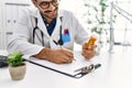 Handsome hispanic man working as doctor writing pills presciption at hospital clinic