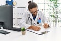 Handsome hispanic man working as doctor writing pills presciption at hospital clinic