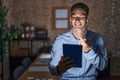 Handsome hispanic man working at the office at night beckoning come here gesture with hand inviting welcoming happy and smiling Royalty Free Stock Photo