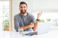 Handsome hispanic man working using computer laptop with a big smile on face, pointing with hand and finger to the side looking at Royalty Free Stock Photo