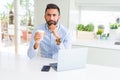 Handsome hispanic man working using computer laptop and drinking a cup of coffee serious face thinking about question, very Royalty Free Stock Photo