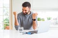 Handsome hispanic man working using computer laptop very happy and excited doing winner gesture with arms raised, smiling and Royalty Free Stock Photo