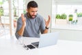 Handsome hispanic man working using computer laptop very happy and excited, winner expression celebrating victory screaming with Royalty Free Stock Photo