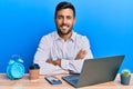 Handsome hispanic man working using laptop at the office happy face smiling with crossed arms looking at the camera Royalty Free Stock Photo