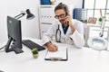 Handsome hispanic man writing presciption on the phone at hospital clinic