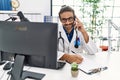 Handsome hispanic man writing presciption on the phone at hospital clinic