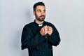 Handsome hispanic priest man with beard praying holding catholic rosary smiling looking to the side and staring away thinking Royalty Free Stock Photo