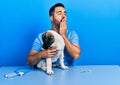 Handsome hispanic veterinary man with beard checking dog health bored yawning tired covering mouth with hand Royalty Free Stock Photo