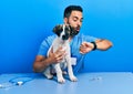 Handsome hispanic veterinary man with beard checking dog health looking at the watch time worried, afraid of getting late Royalty Free Stock Photo
